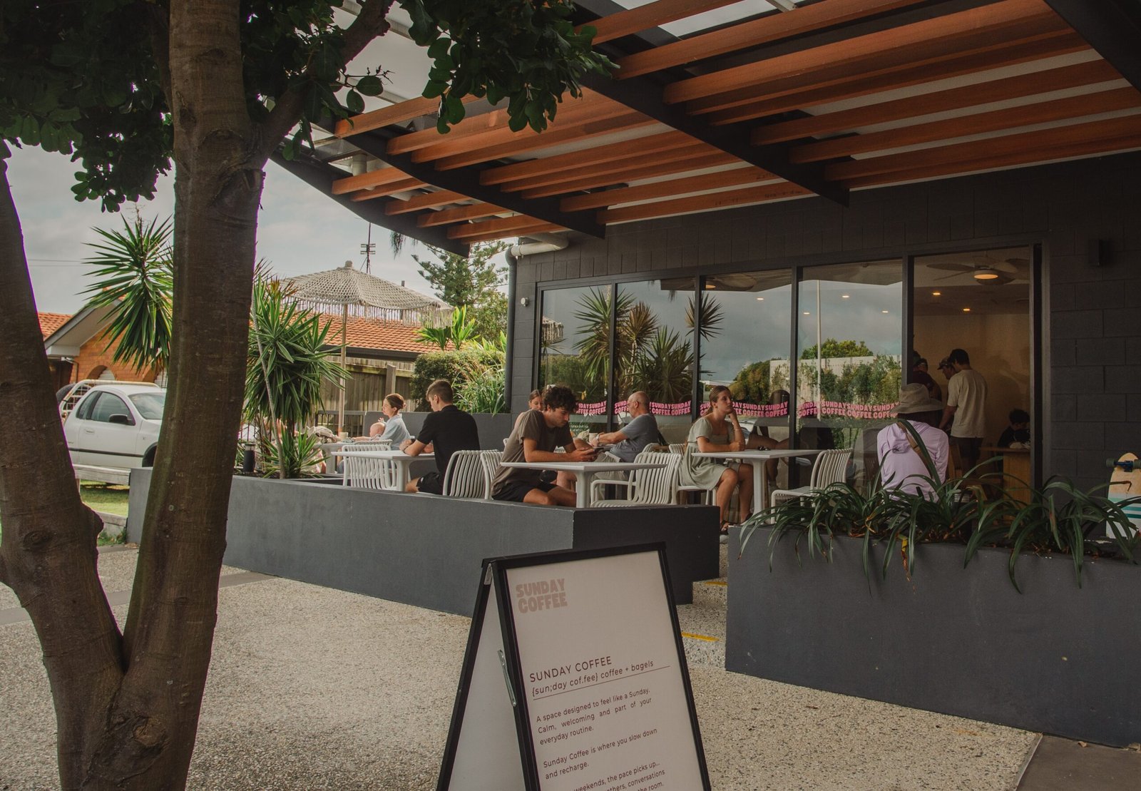 Outdoor seating area of Sunday Coffee in Buddina, featuring patrons enjoying coffee, surrounded by greenery and a welcoming atmosphere.